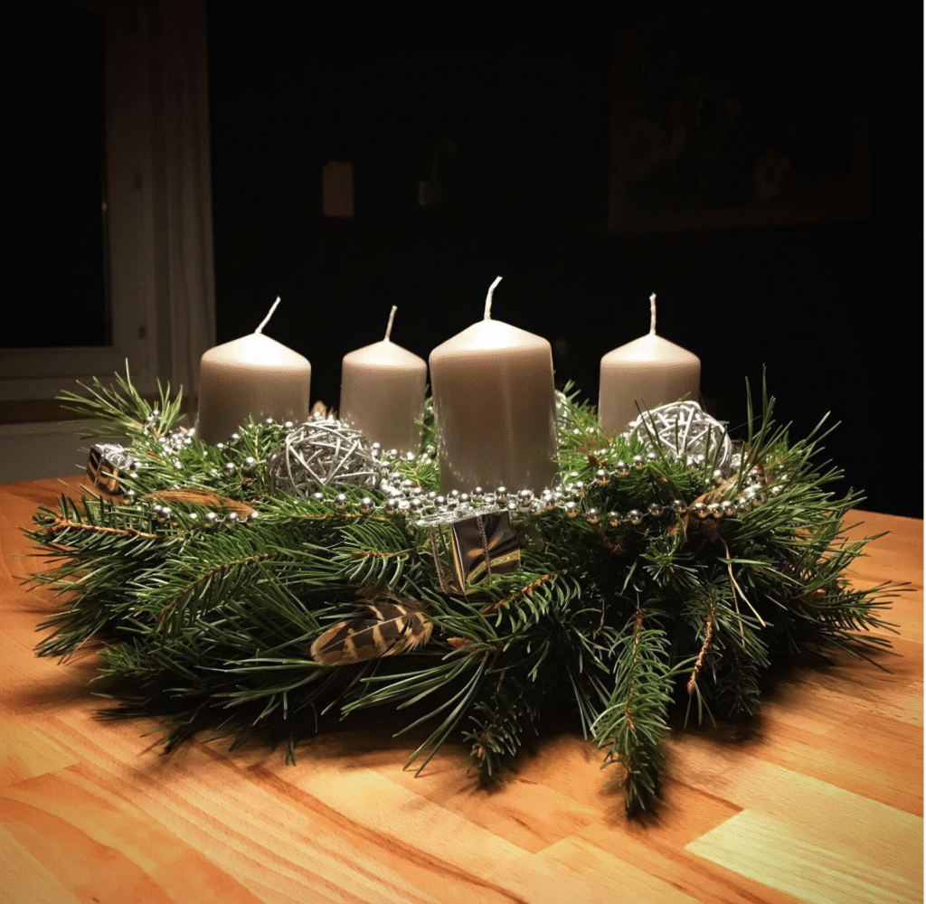Adventkranz mit Federn und silbernen Girlanden und Kugeln.
