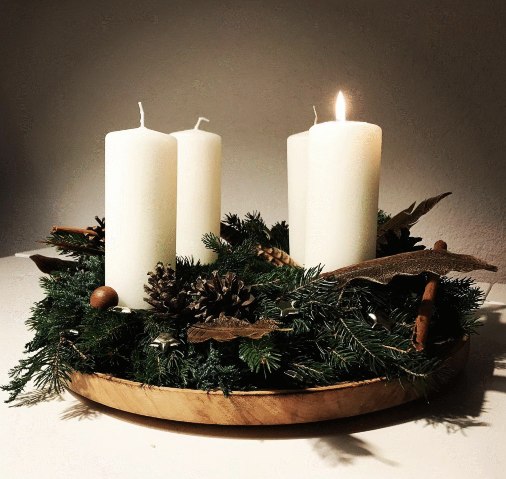 Adventkranz mit Fasenenfedern, Zapfen und Zimtstangen.